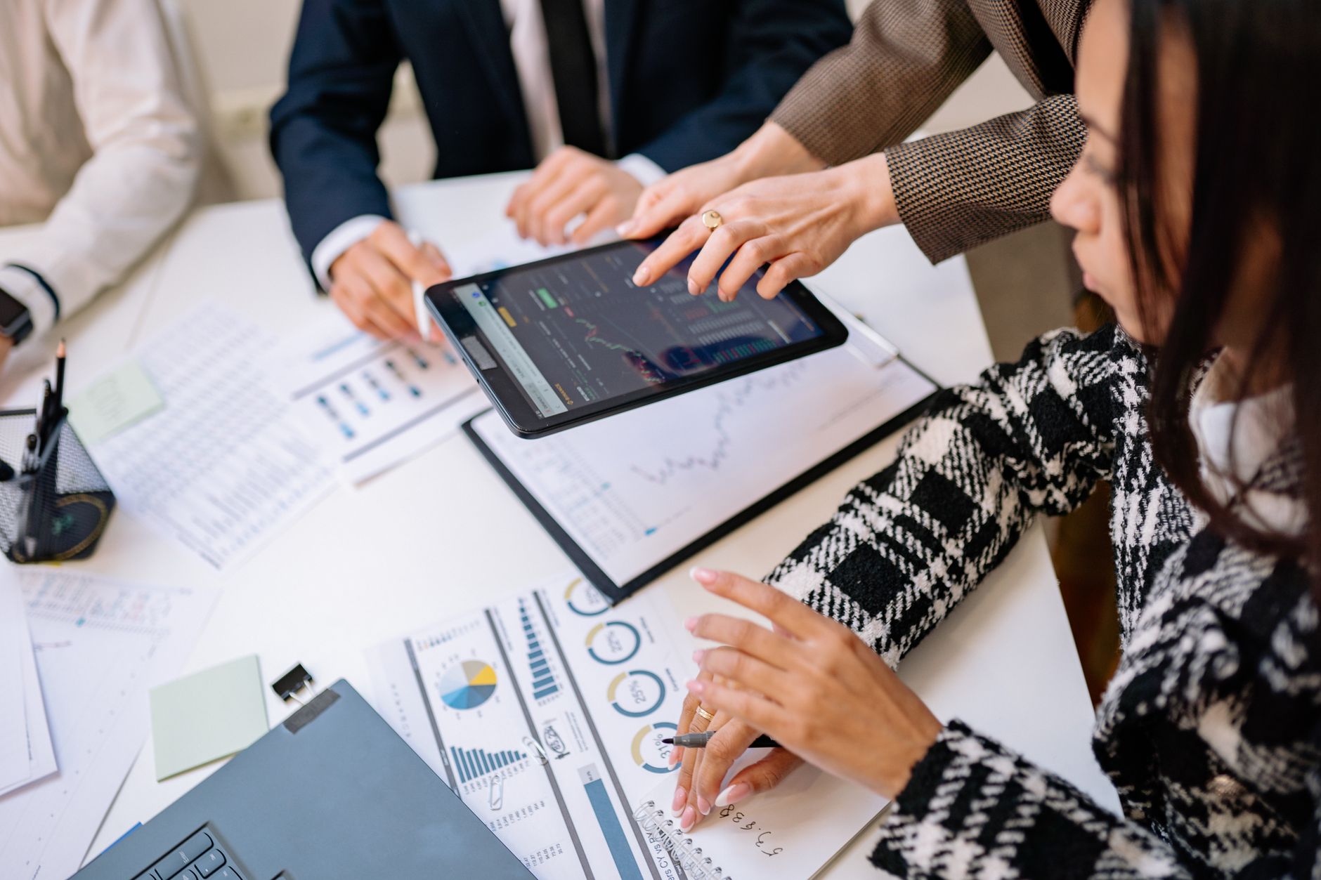 Group of business partners looking at dynamic charts on digital tablet